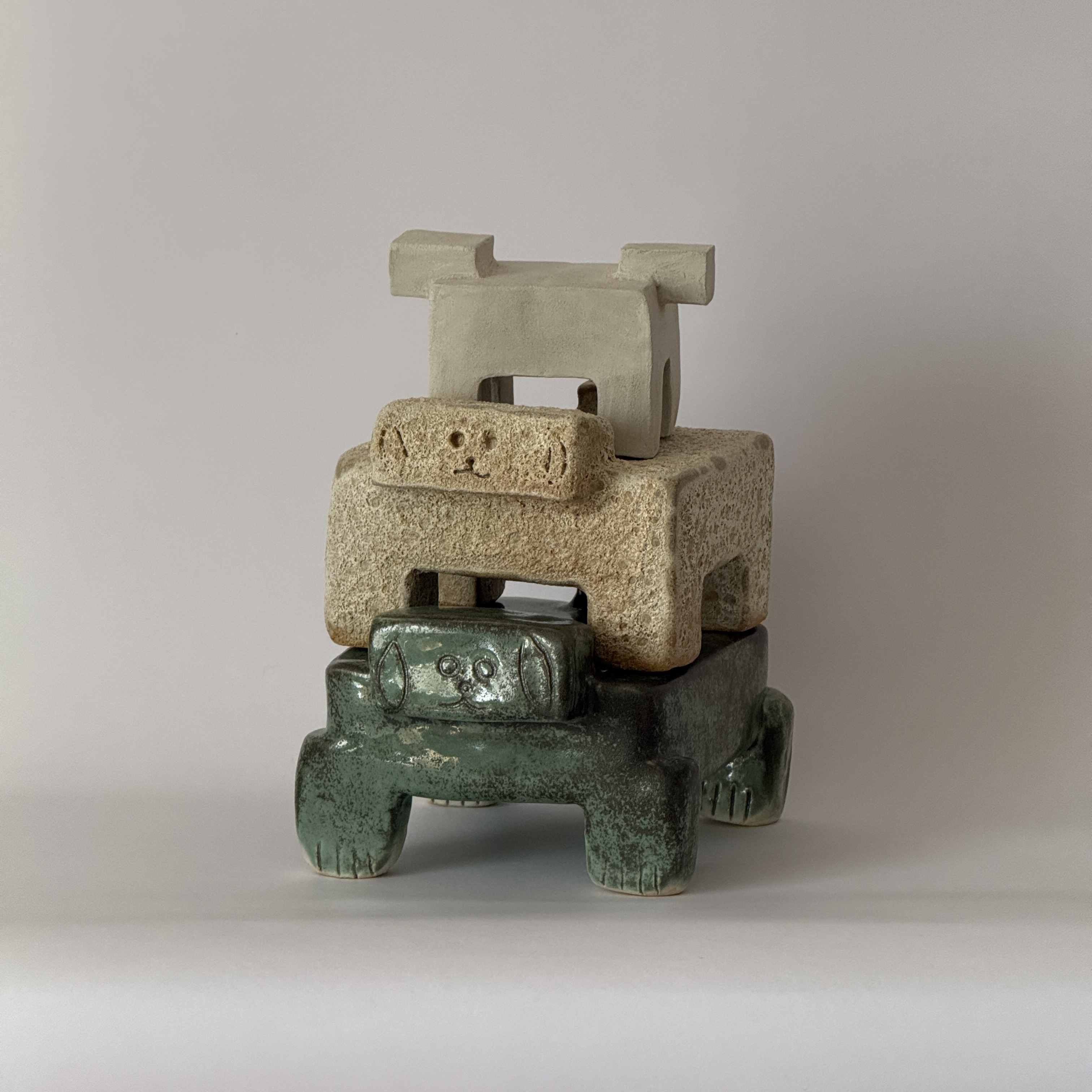 Tres figuras de cerámica apiladas en crema y verde